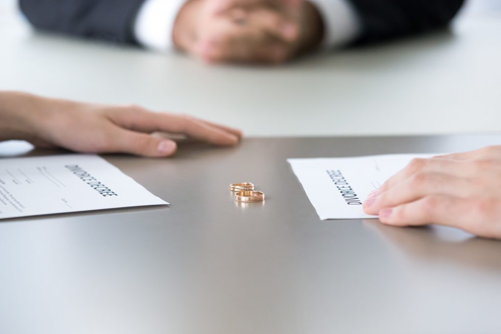 Close up of rings and divorce decree lying on table.