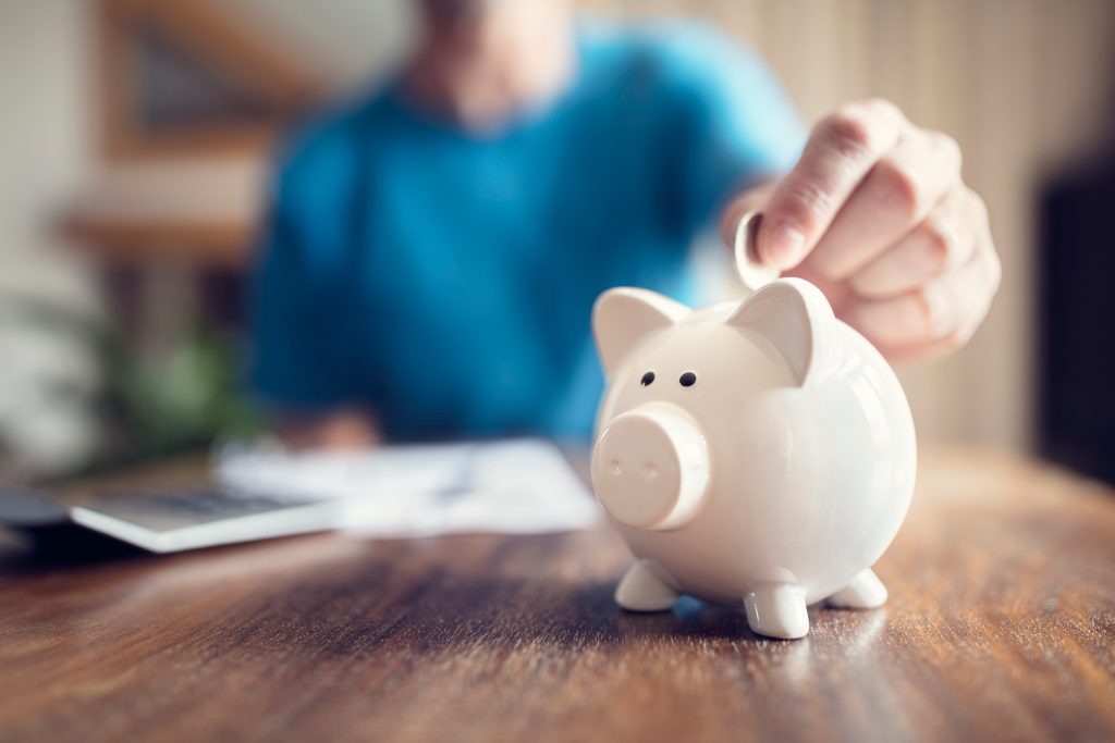 Man placing coin in piggy bank.