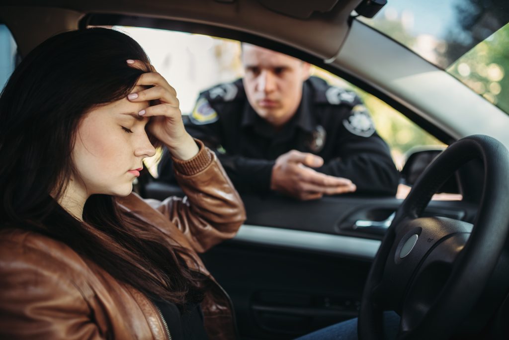 Male cop in uniform check female driver on road.