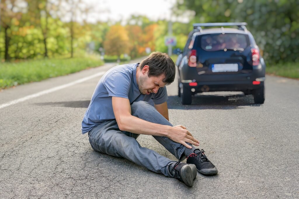 Hit And Run Concept. Injured Man On Road In Front Of A Car.