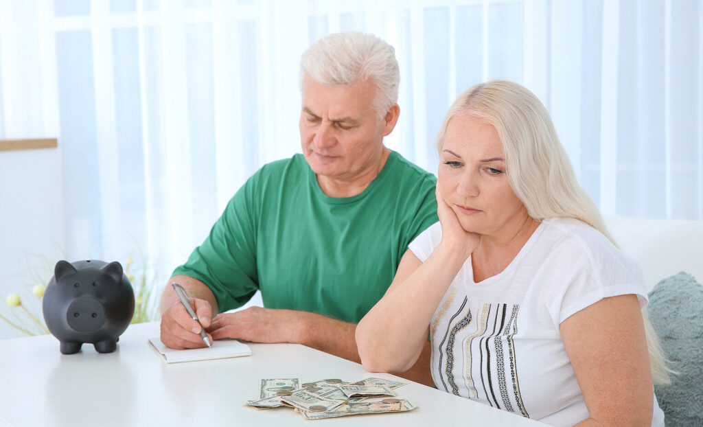 Mature Couple With Money And Piggy Bank At Table