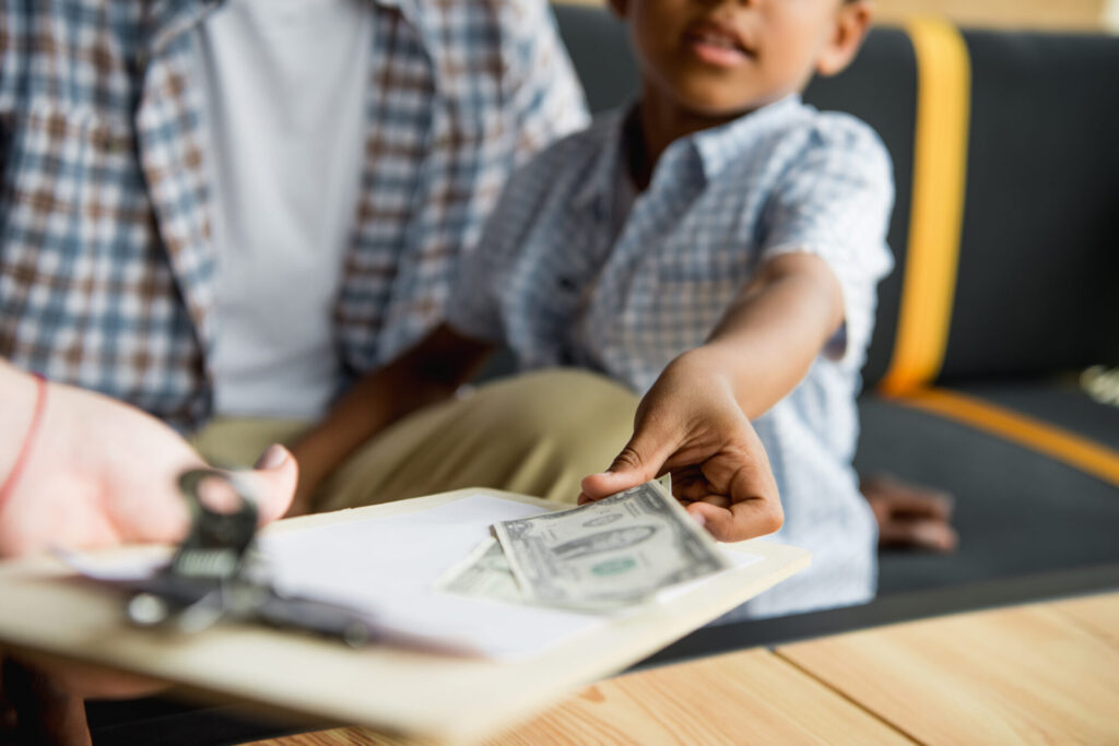 cropped shot of father and son paying money while waiter holding bill